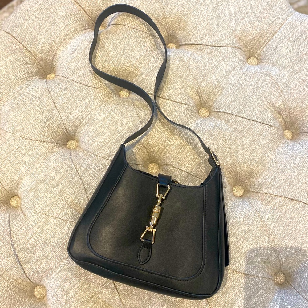 Brand New-Shoulder bag-med sized black faux leather with gold clasp detail.